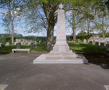 Das Bild zeigt ein weißes Denkmal mitten auf dem Friedhof